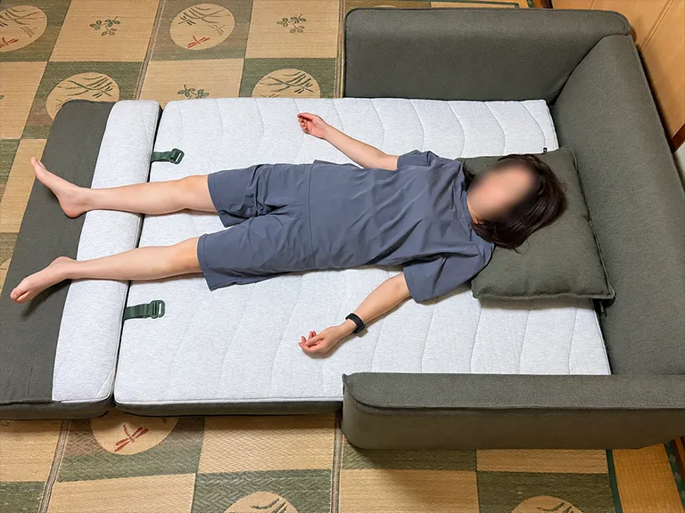 ベッドに展開したCUSHY+に横になり寝心地を検証する様子